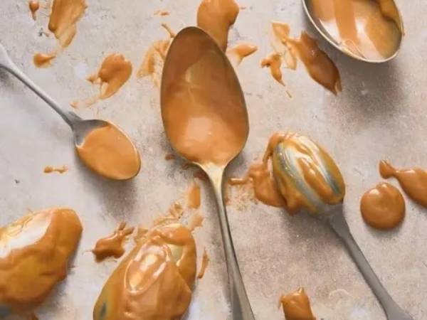 Close-up messy spoons coated in peanut butter