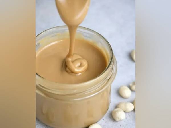 Creamy nut butter being poured into jar