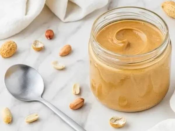 Open jar of creamy peanut butter with spoon