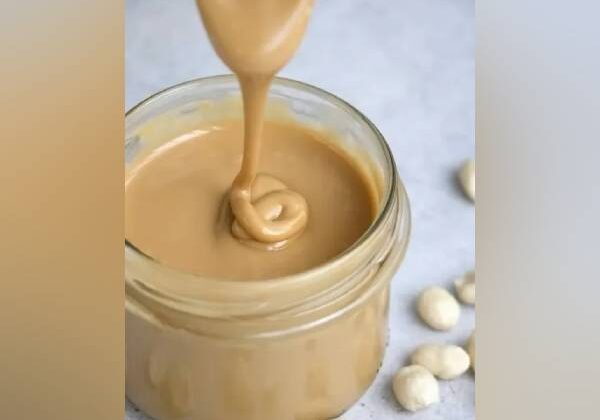 Creamy nut butter being poured into jar