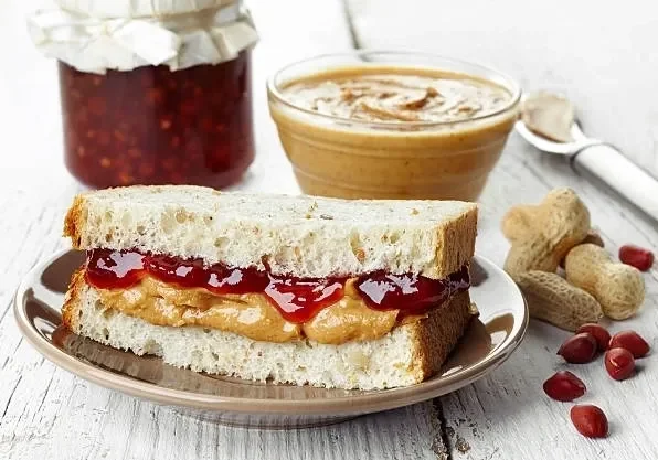 Half peanut butter and jam on bread with sauces around