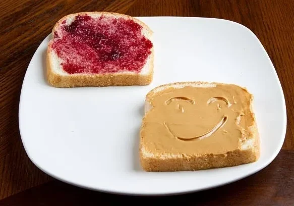 Smiley peanut butter slice next to jelly