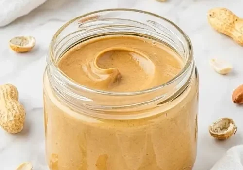 Jar of creamy peanut butter with peanuts